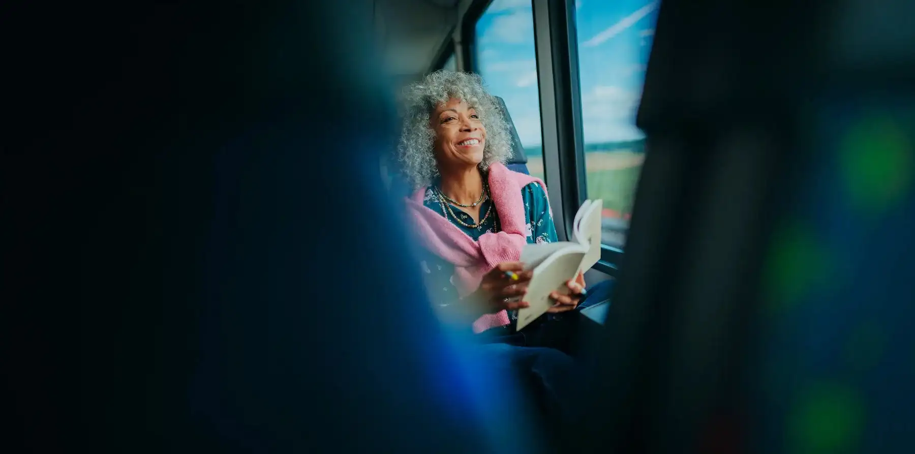 Femme souriante lisant dans le train