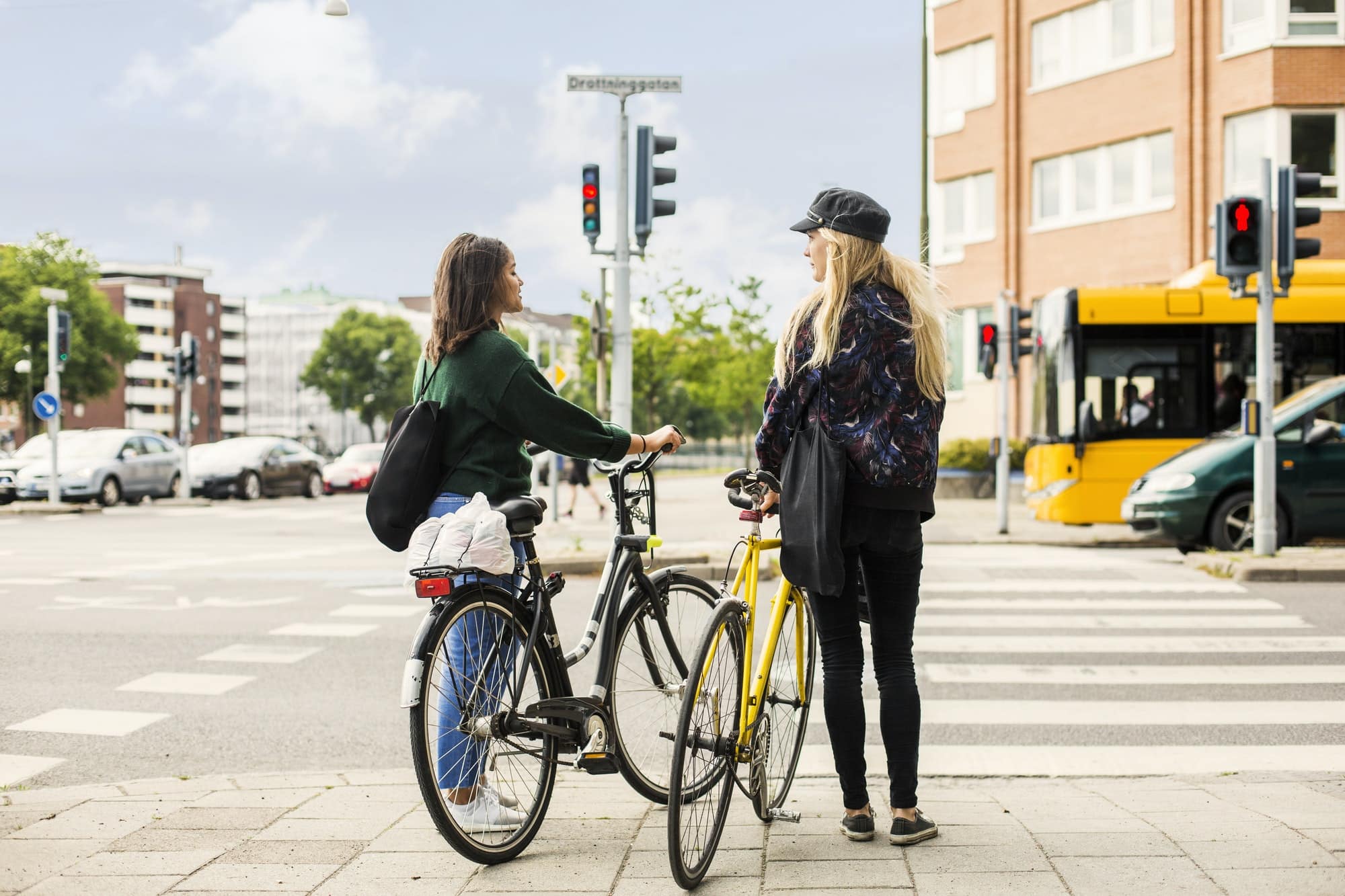 Two young women pushing bikes in town